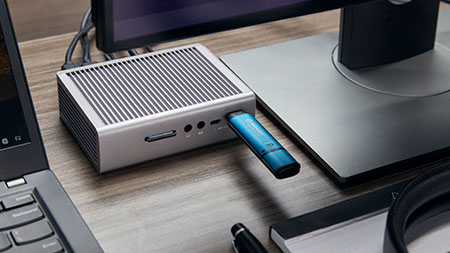 A Kingston IronKey Vault Privacy 50 USB is plugged into a multi-port hub on a desk, connected to an office computer.